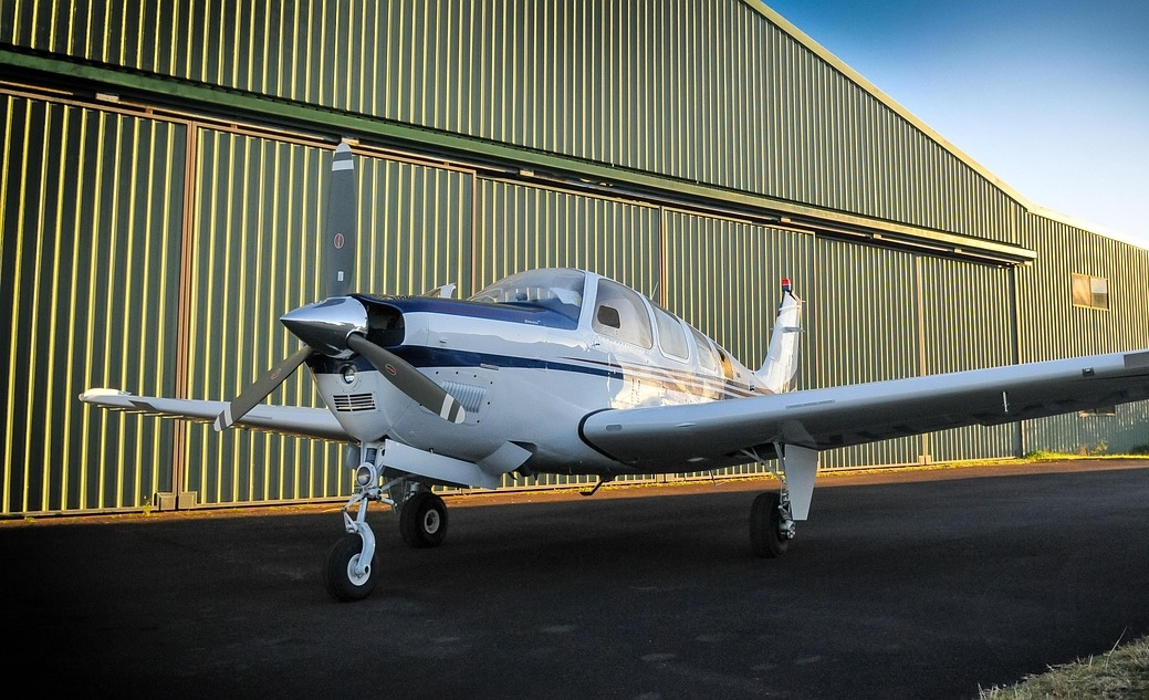 A small plane parked infront of a hanger.